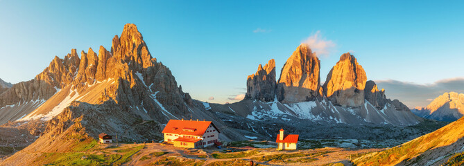 Panoramic view of mountain sunrise at Tre Cime di Lavaredo National park and rifugio Locatelli in Dolomites Alps, Trentino Alto Adige, Italy. Alpine landscape with huts and rock