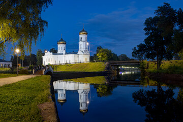 Epiphany Cathedral, Vyshny Volochyok, Tver region, Russia. Evening landscape. In the foreground is the Tsninsky Canal. A beautiful white church and trees are reflected in the water. Twilight.