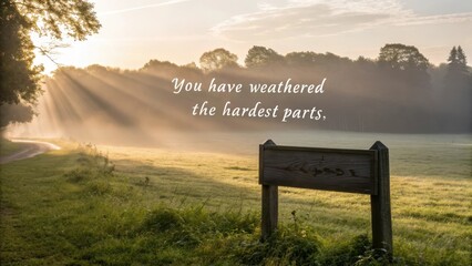 Sunlight Pierces Through Mist Over Open Field with Inspirational Quote