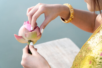 Lotus Blossom Care: A gentle hand delicately holds a serene lotus flower, offering a sense of peace and contemplation near the water. The image reflects an atmosphere of tranquility.