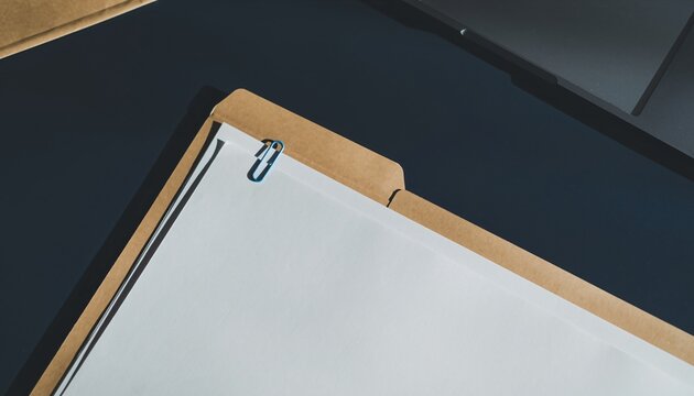 Manila folder with white papers and a blue paper clip on a dark desk, ready for organization.