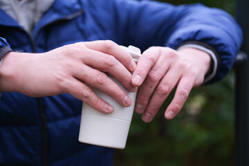 Close-up of hands holding a reusable coffee cup outdoors