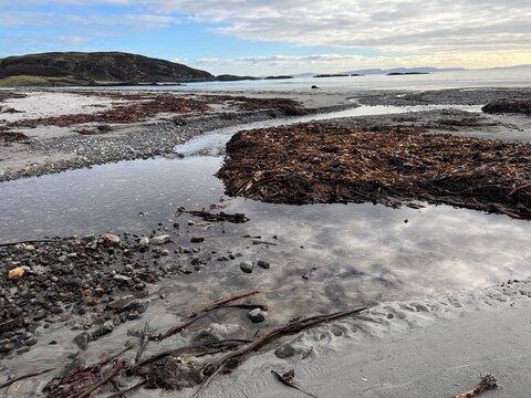 Beautiful wild beach Isle of Mull Scotland Uisken the beautiful rocky and sandy shore sunrise with water pools reflect sun light  vast ocean on horizon with wildlife  and blue sky in Winter no people