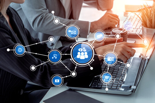 Two professionals working together at a desk with laptops, surrounded by digital icons representing connectivity and social media engagement in a sleek modern office. Tessel - Powered by Adobe