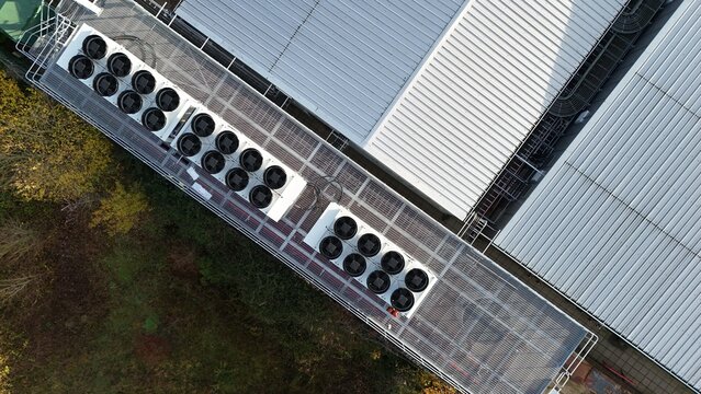 Aerial drone top down rotating view of cooling and ventilation systems on a data storage center warehouse building showing modern infrastructure.