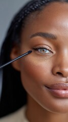 African american woman applying mascara, focusing on beauty, makeup, and skin care