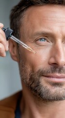 Man applying a cosmetic serum directly to his face with a dropper for beauty care