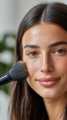Young woman brightening her face with a makeup brush, focusing on beauty ritual
