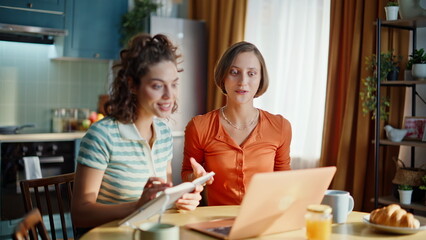 Two students talking webcam laptop having online conference home. Smiling girl