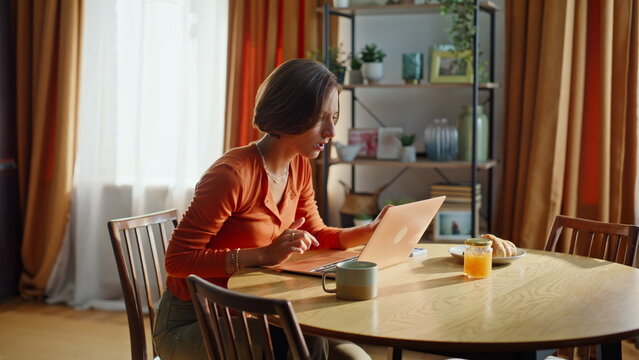 Stressed brunette closing laptop reading bad news in kitchen. Frustrated woman