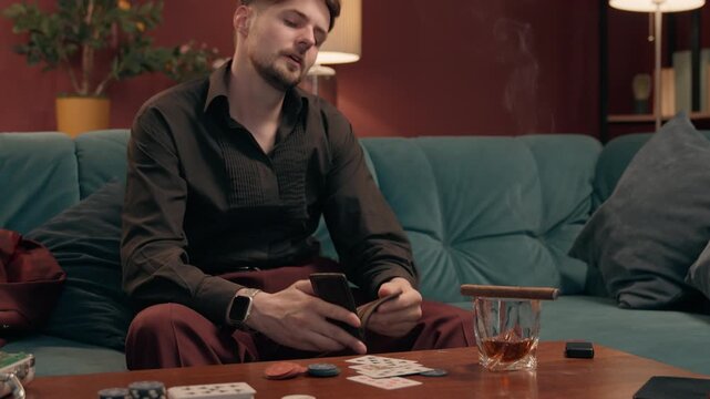 Frustrated Caucasian male gambler looking empty wallet losing money casino poker disappointed broke man guy player cash bankruptcy betting loss gambling addiction game playing failure at home indoors