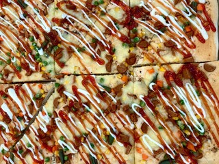 top view of square cut pizza slices with colorful vegetable toppings and sauces