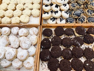 assorted colorful glazed and topped donuts displayed in a bakery shop window