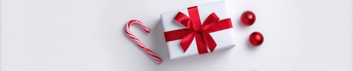 Festive Christmas gift box with red bow and candy cane flat lay
