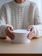 Gift giving moment with elderly hands holding a white box in cozy sweater