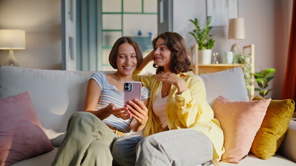 Videocalling friends talking smartphone enjoying friendly communication at home.