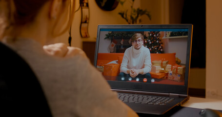 Young woman connecting with boyfriend through video call, sharing Christmas spirit and festive joy from cozy home interior during winter holiday season