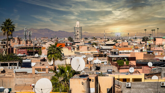 Desert City Rooftops With Satellite Dishes At Sunset, Palm Trees And Distant Mountains, Marrakesh, Morocco