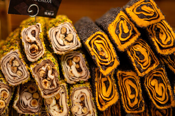 Turkish sarma lokum rolled dessert with nuts and pistachios stacked at traditional market