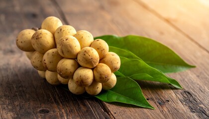 Fresh langsat or duku tropical fruit cluster with green leaves on wooden background, natural Asian fruit and healthy food concept