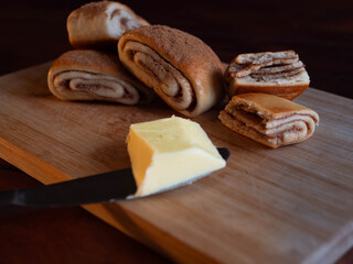 Freshly baked cinnamon rolls dusted with spice on a rustic wooden board with butterknife