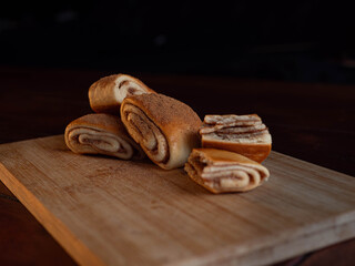 Freshly baked cinnamon rolls dusted with spice on a rustic wooden board with butter