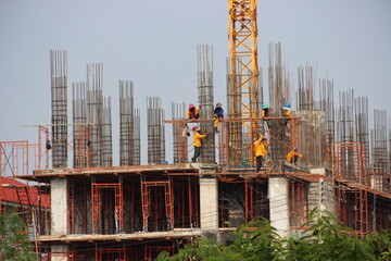 Construction workers are sitting and tying rebar for the building structure.