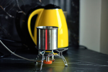 Portable gas stove and metal pot on black countertop during blackout