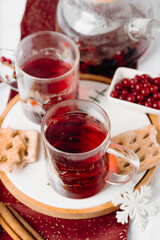 Glasses of red winter drink on wooden tray with cookies. Cozy holiday beverage and festive home styling.