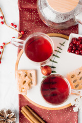 Top view of red winter drink served in glass cups with cookies and festive decor. Cozy holiday tea scene and warm seasonal mood.