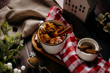 Cozy winter snack tray with cookies and hot drink on red checkered textile. Warm holiday food styling and home comfort atmosphere.
