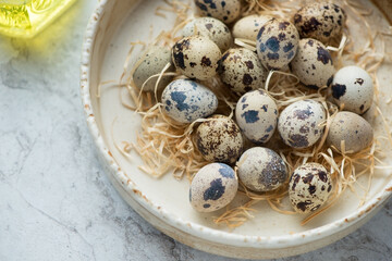 Middle close-up of fresh uncooked quail eggs in a beige bowl, horizontal shot, selective focus