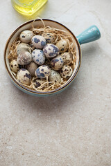 Turquoise serving bowl with raw quail eggs, vertical shot on a beige stone background with space, elevated view