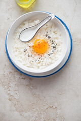 Japanese-style rice and egg bowl on a light-beige stone background, vertical shot with copy space, view from above
