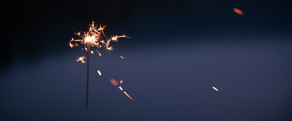 Close-up of a burning sparkler in the evening dusk. Horizontal background for christmas and new year's with space for text.