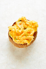 Diet scrambled eggs on toasted brioche bun on light background