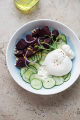 Plate with burrata cheese, beetroot and cucumber salad, vertical shot on a beige granite background, elevated view