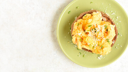 Diet scrambled eggs on toasted brioche bun on green plate