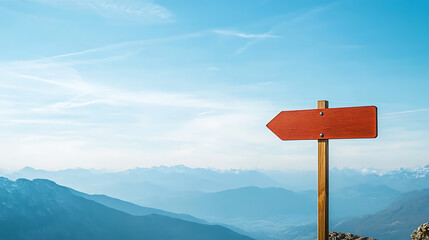 Directional sign atop a mountain peak, pointing left against a vast expanse of blue sky and distant mountains. An image of choice, adventure, and clear skies on the horizon.