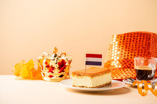 Stack of orange tompouce and donuts glazed donuts with red, white and blue sprinkles topped with a small Dutch flag on wooden board. National holiday Koningsdag on 27 April in the Netherlands