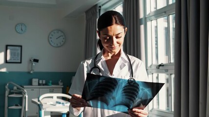 female doctor examining x-ray image, medical professional in coat with stethoscope, bright hospital interior, confident healthcare worker smiling while analyzing radiology scan - Powered by Adobe