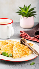 Delicious golden pancakes served with honey and fresh mint on a stylish table setting