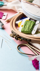 Colorful embroidery supplies arranged on a pastel background with threads, needles, and scissors