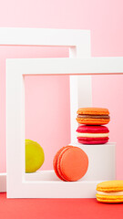 Colorful macarons arranged in white frames on a vibrant pink background with playful composition