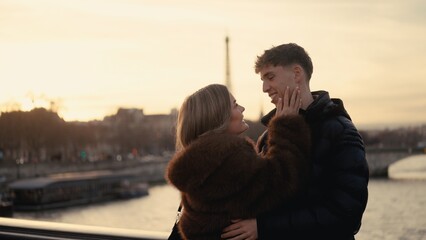 A romantic couple embraces in Paris France with the Eiffel Tower visible in the background at sunset. This image is perfect for illustrating themes of love travel and European vacations. © 4kclips