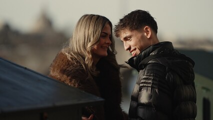 A romantic couple smiles at each other in Paris France showing love and affection They are wearing winter coats and jackets on an outdoor date during They.