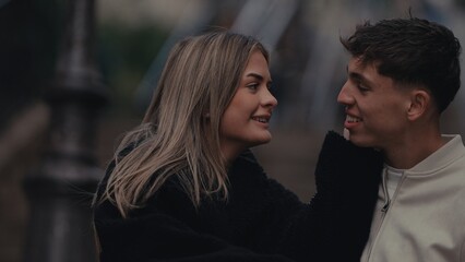 A young couple in Paris France share a romantic moment smiling at each other with love and...