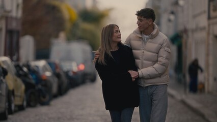 A romantic couple walks together on a cobblestone street in Paris France embracing with love and...