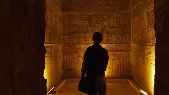 A female tourist admires the interior of the temple in Dendera or the temple of Hathor in Egypt. Ancient hieroglyphic carvings on the temple walls. The history of Egypt.