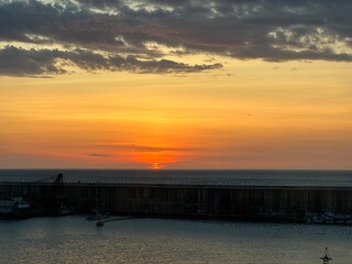 Fototapeta premium Beautiful sunset over the ocean horizon viewed from a fishing harbor.